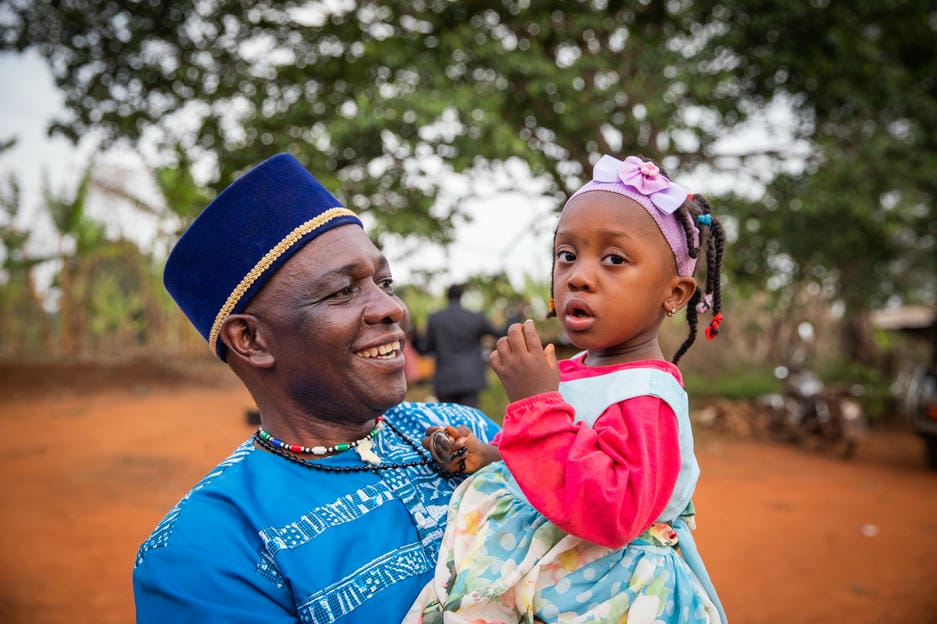 African grandfather happily looks at his granddaughter as he holds her in his arms