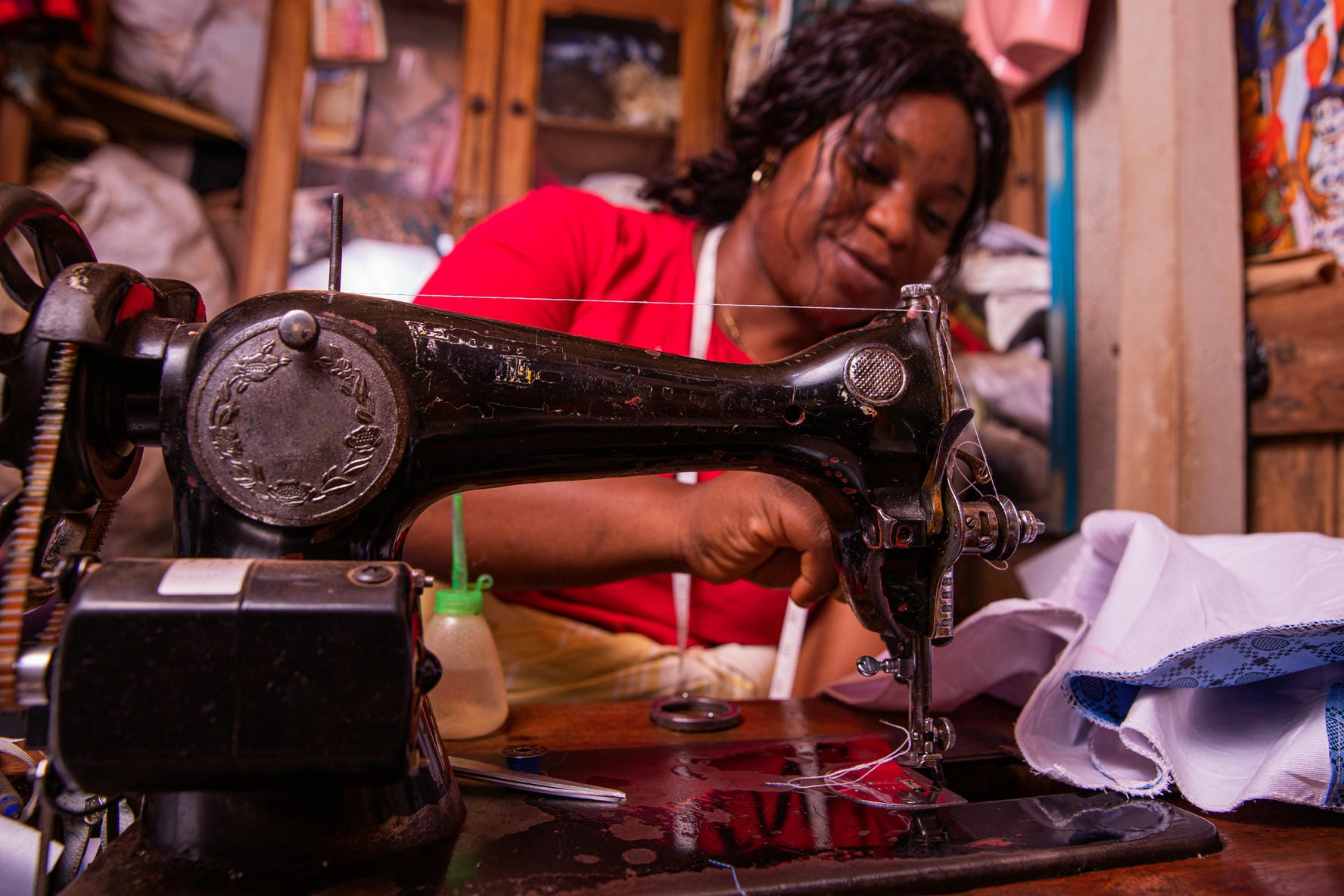 An African seamstress sews a dress with her sewing machine. Working female in her tailor shop
